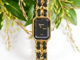 an image of a black and gold watch sitting on top of a green plant