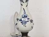 a blue and white vase with a gold handle on a stand