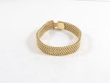 gros plan d'un bracelet en or sur une surface blanche