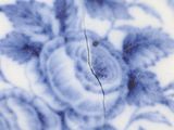 a close up of a blue and white plate with a crack in the middle