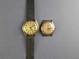 two watches are sitting next to each other on a gray surface