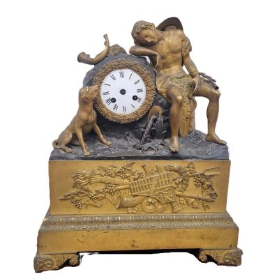 une horloge en or surmontée d'une statue représentant un garçon et un chien