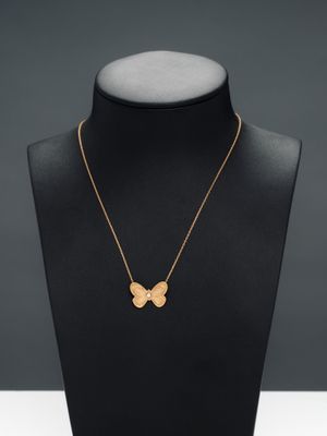 un collier en or avec un pendentif en forme de papillon sur un mannequin
