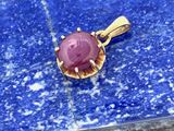 un gros plan d'un pendentif en pierre rose sur un fond bleu