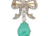 un gros plan sur une broche en forme d'arc, composée d'une pierre verte et de diamants