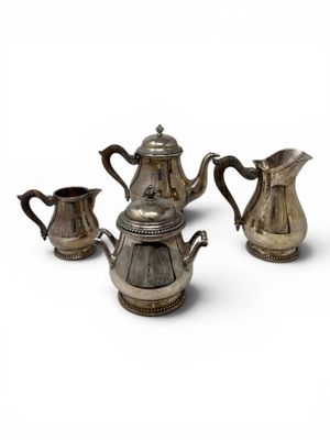 three pieces of silver tea and coffee set on a white surface