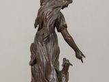 bronze statue of a woman and a dog on a wooden table