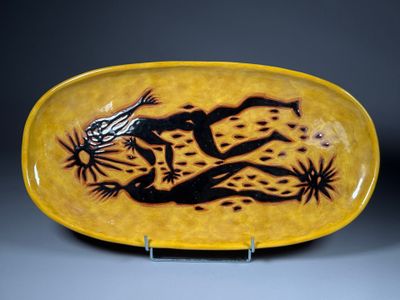 une assiette jaune et noire sur laquelle est représenté un lézard