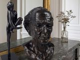 a statue of a man sitting on a table next to a vase of flowers