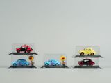 Plusieurs petites voitures sont exposées dans une vitrine posée sur une surface blanche
