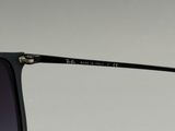 Les lunettes de soleil sont noires et comportent une barre métallique en haut de la monture.