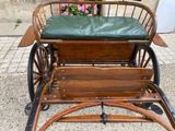 a wooden carriage with a green seat on it