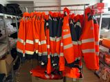 many orange safety jackets hanging on a rack in a room