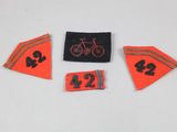 three patches with numbers and a bicycle on them on a white surface