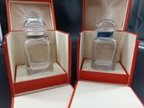 two bottles of perfume are in a red box on a table