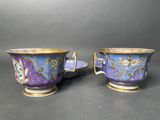 pair of blue and gold cups and saucers with floral designs