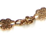 a close up of a gold bracelet on a white surface