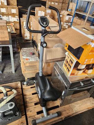 an image of a stationary exercise bike in a warehouse with boxes on the floor