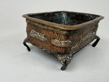 a small metal pot with a handle on a stand