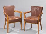 deux fauteuils en cuir marron placés l'un à côté de l'autre sur une surface grise