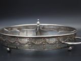 an antique silver plate with handles and handles on a black surface