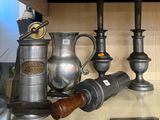 a glass shelf with silver vases and other items on it