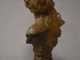 a bronze busturine of a woman with long hair