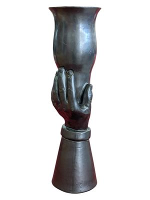 un vase en métal orné d'une main, sur fond blanc