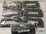 Six sacs Adidas sont emballés dans du plastique sur une table