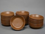six assiettes marron empilées les unes sur les autres sur une surface grise