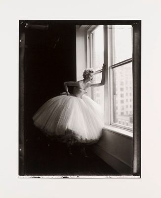 photographie en noir et blanc d'une femme en tutu posant devant une fenêtre