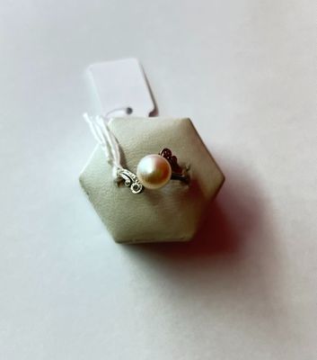 une petite boîte blanche ornée d'une perle et d'une perle en argent