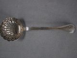 une cuillère en argent ornée d'une fleur, posée sur un fond gris