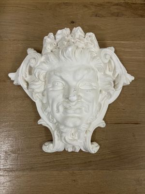 a white sculpture of a man ' s face on a wooden table