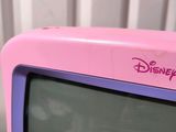 pink and purple television sitting on top of a table next to a white wall