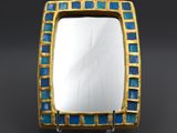 a gold and blue mosaic glass mirror on a stand