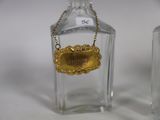 two bottles of perfume with a gold label and a chain