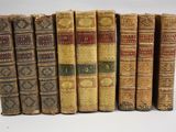 six vieux livres sont alignés sur une surface blanche