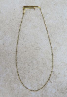 a gold necklace with a bar on it sitting on a white surface