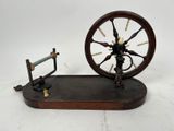 a small spinning machine with a wooden base on a white surface