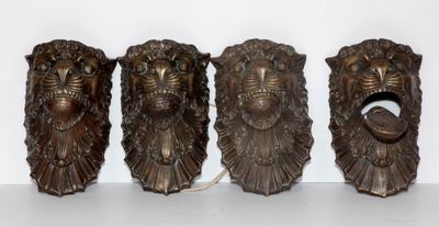 trois têtes de lion en bronze sont posées sur une surface blanche