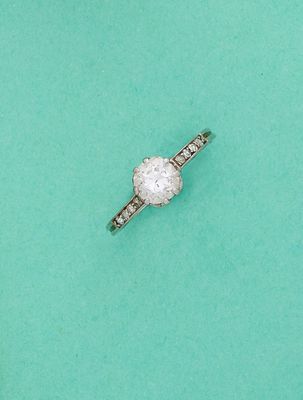 une bague en diamant posée sur un fond vert, avec un diamant au centre