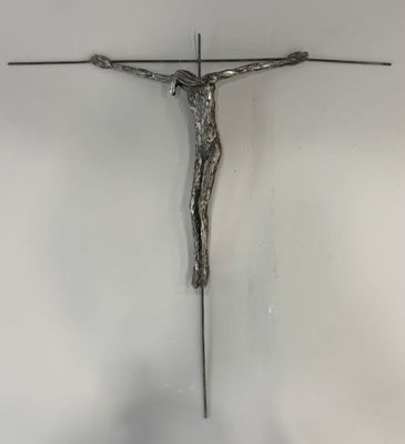 un crucifix en métal accroché au mur d'une pièce blanche
