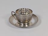 a silver cup and saucer sitting on a saucer