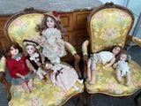 five dolls sitting on a yellow chair in a room