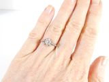 a woman ' s hand with a diamond ring on it