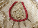 a red necklace with gold spikes on it on a woven tray