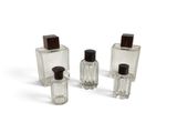 trois bouteilles en verre transparent avec des bouchons noirs et un bouchon en bois brun