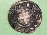 an old coin with a cross on it sitting on a green surface