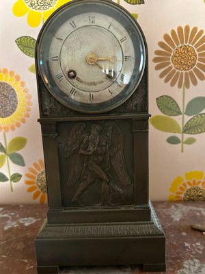 une horloge posée sur une table, avec des fleurs en arrière-plan